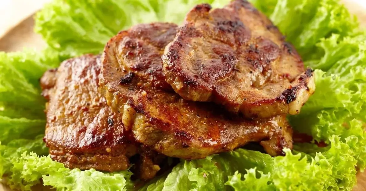 Marynowana karkówka z grilla ułożona na liściu sałaty.