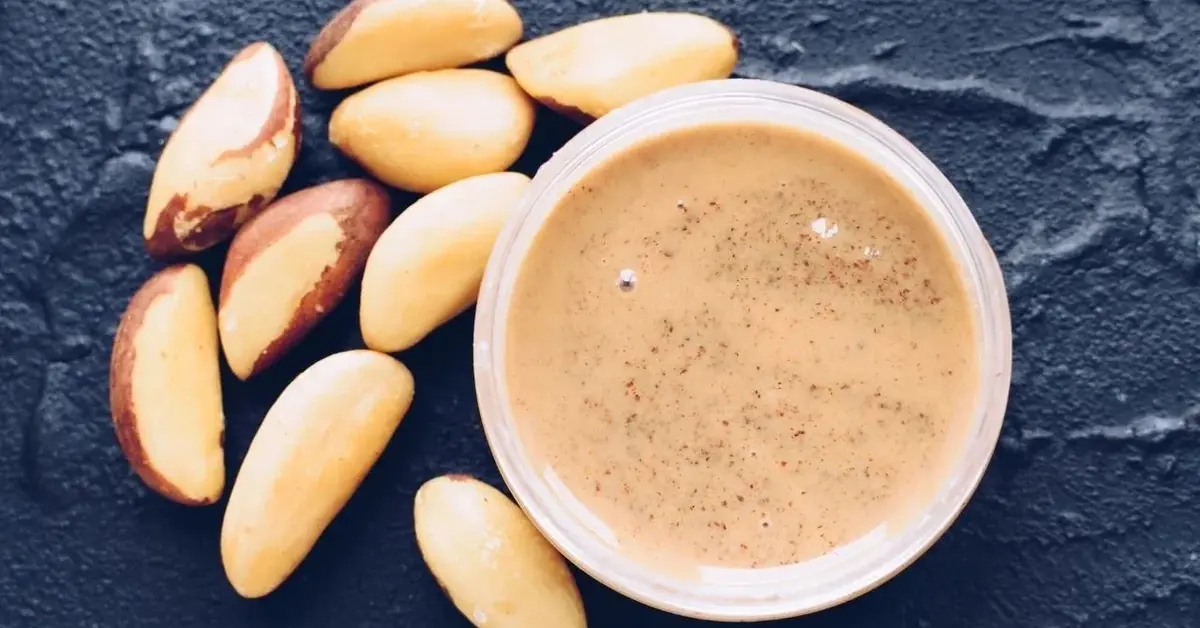 gotowe masło z orzechów w białej misce i kilka obranych orzechów brazylijskich