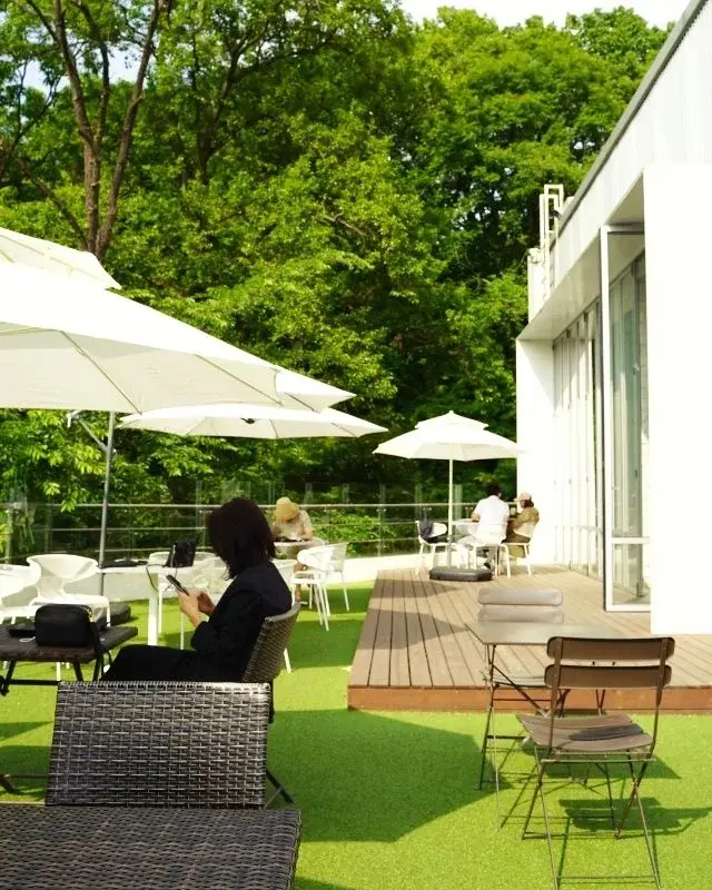 Komplet technorattanowych mebli ogrodowych w zielonym ogrodzie z białymi parasolami