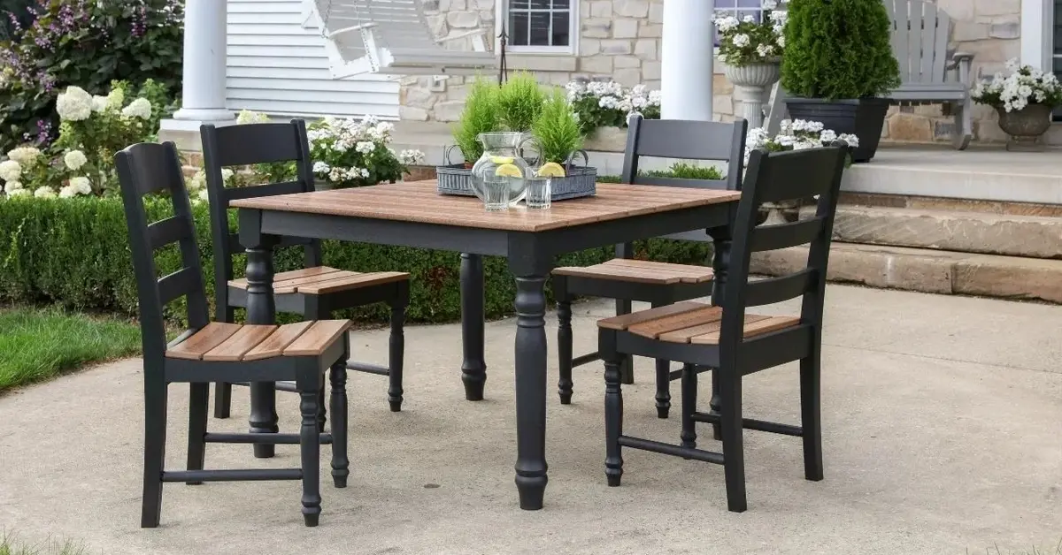 Komplet ogrodowy drewniano-metalowy złożony ze stołu i 4 krzeseł na kamiennym tarasie domu