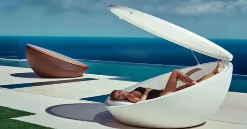 Futurystyczny fotel ogrodowy biały z leżącą kobietą przy basenie
