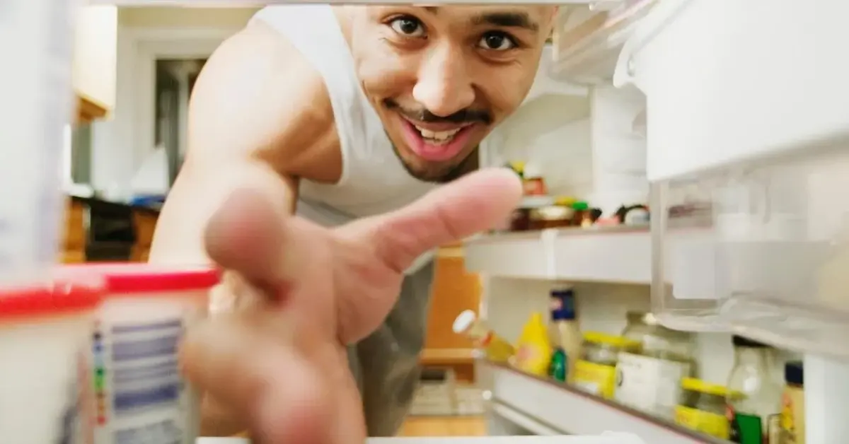 Uśmiechnięty mężczyzna wkłada pochłaniacz zapachu do lodówki