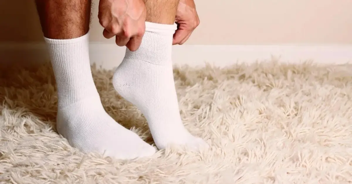 Mężczyzna zakłada śnieżnobiałe, doprane skarpetki.