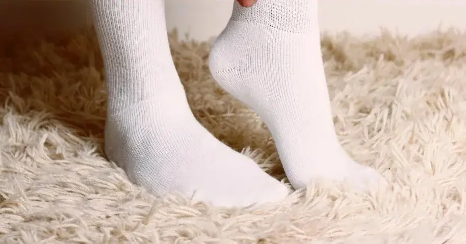 Mężczyzna zakłada śnieżnobiałe, doprane skarpetki.