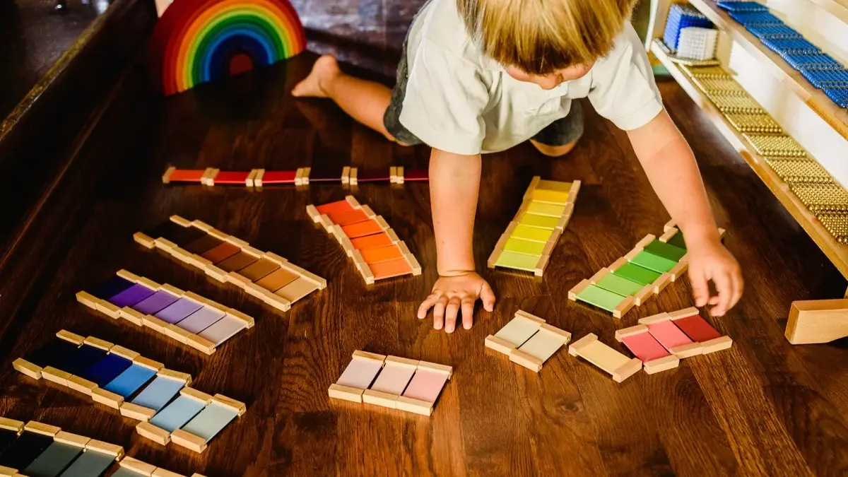 dziecko układa kolorowe elementy dopasowując do siebie na podłodze, montessori