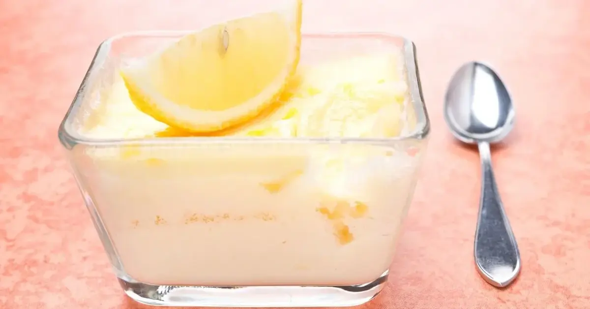 Mrożony krem cytrynowy udekorowany ćwiartką świeżej cytryny, podany w szklanej miseczce