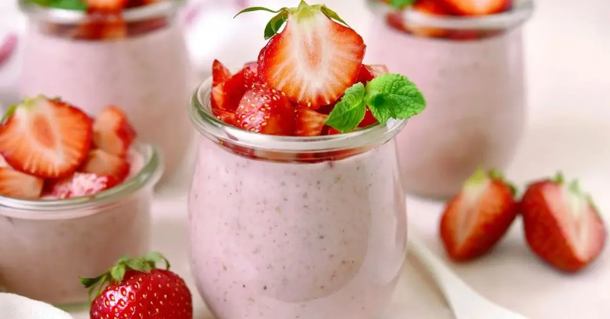 Lekki mus truskawkowo-malinowy z rabarbarem podany w szklanych słoiczkach, udekorowany świeżymi truskawkami