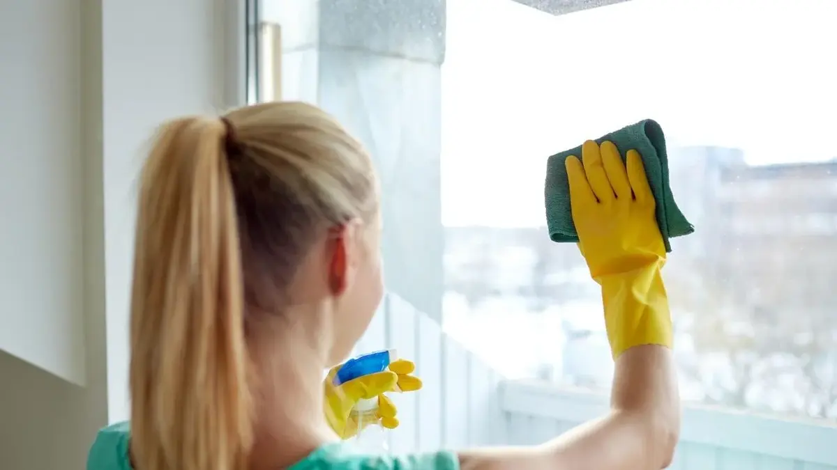 Kobieta myje i poleruje okna.