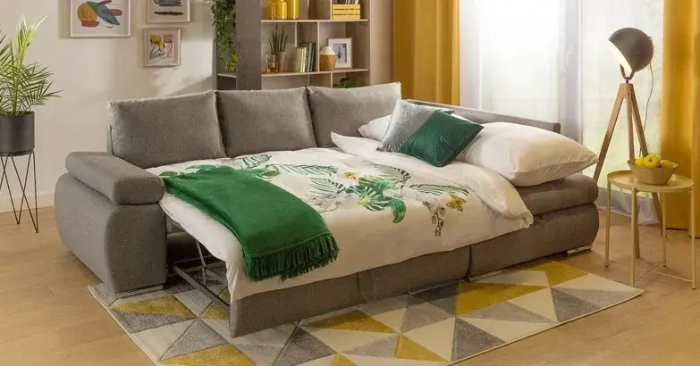 Przytulny salon z funkcją sypialni z rozłożonym szarym narożnikiem z funkcją spania