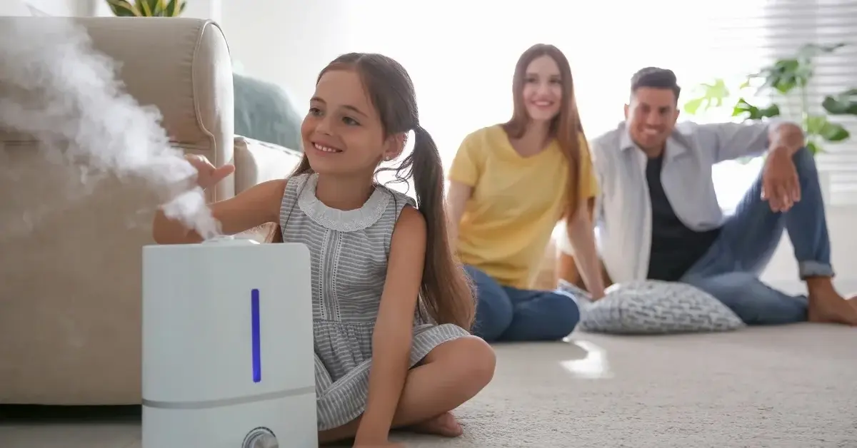 rodzina z córką siedzą na dywanie i patrzą z uśmiechem na nawilżacz powietrza