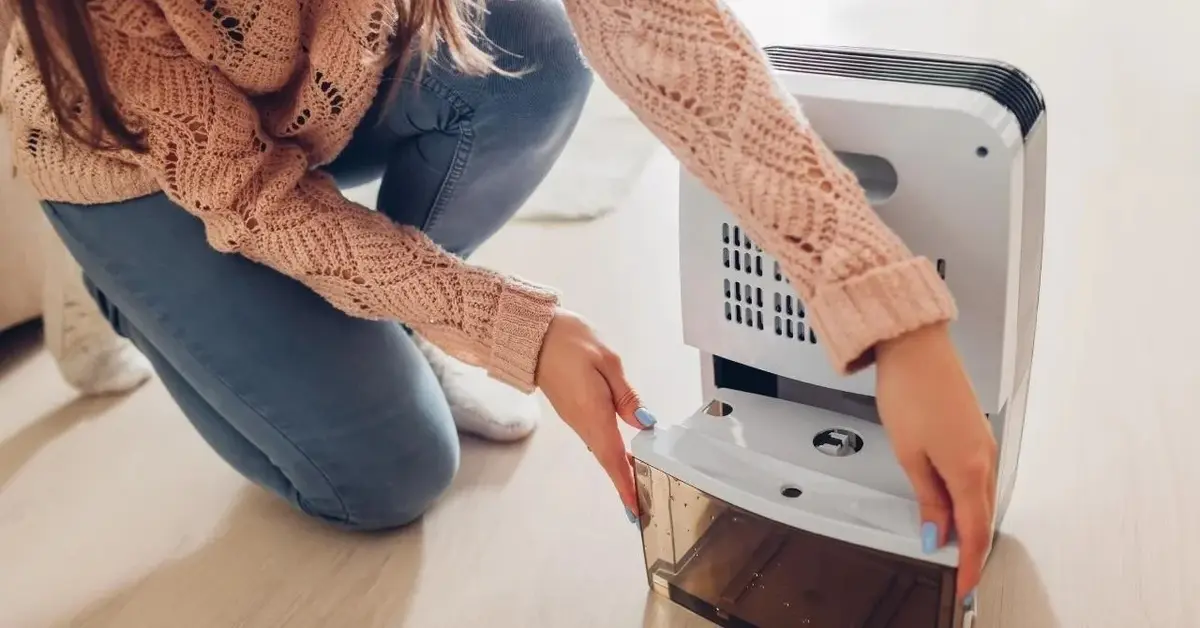 Kobieta wymienia wodę w nawilżaczu, żeby w mieszkaniu była odpowiednia wilgotność.