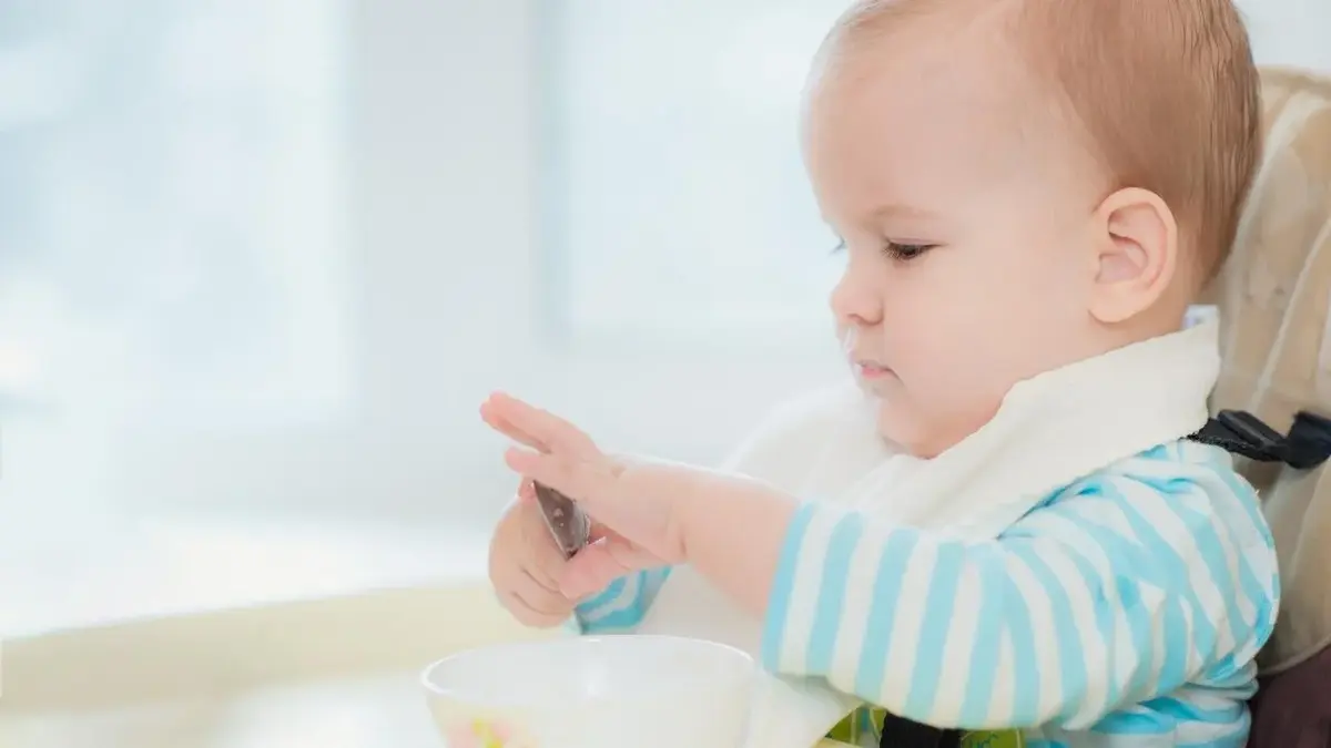 Dziecko w trakcie rozszerzania diety, je samo łyżeczką.