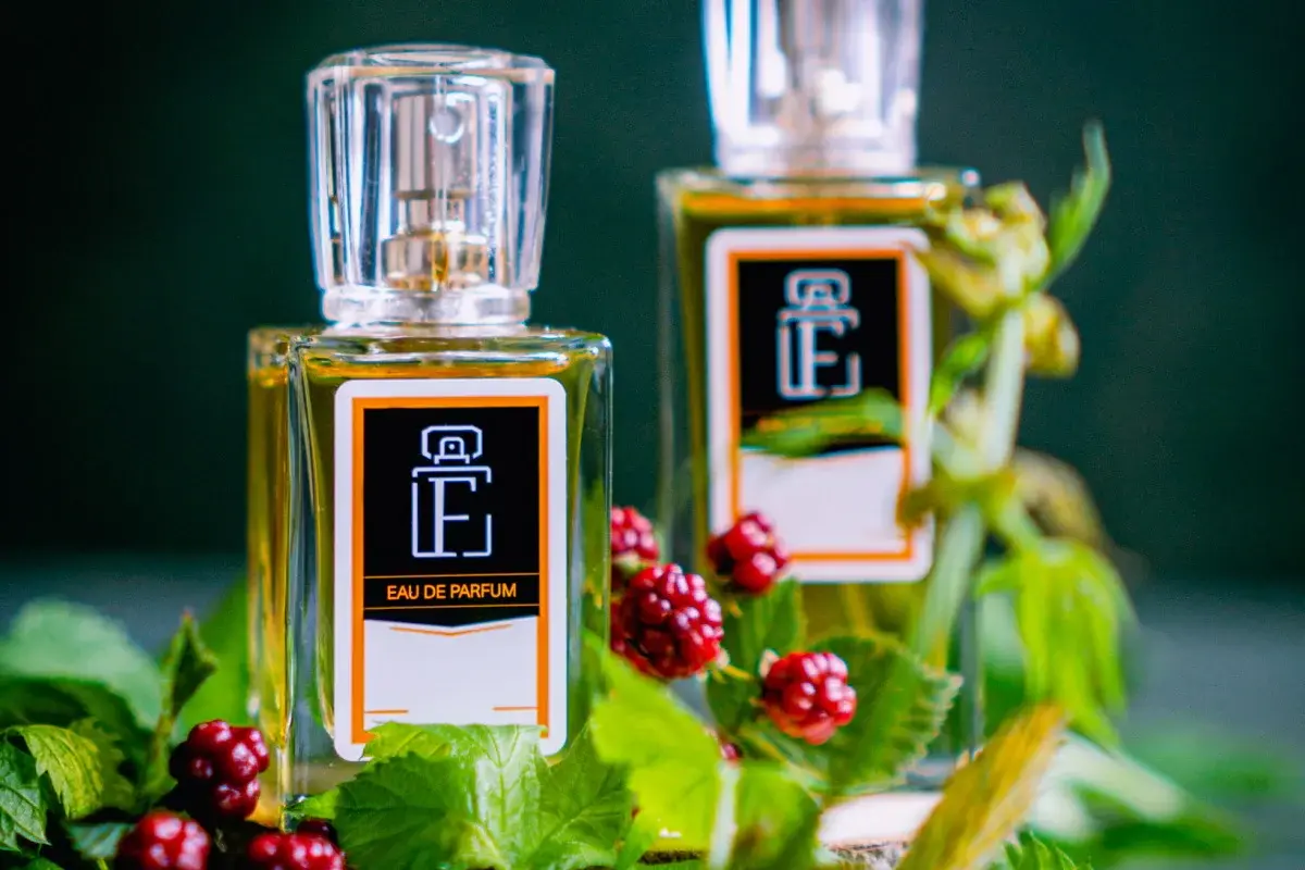 Wśród zielonolistnych roślin z czerwonymi jagodami dwa flakony eleganckich odpowiedników perfum