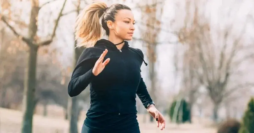 Kobieta blond kucyk w odzieży do biegania w zimie w czasie joggingu w parku