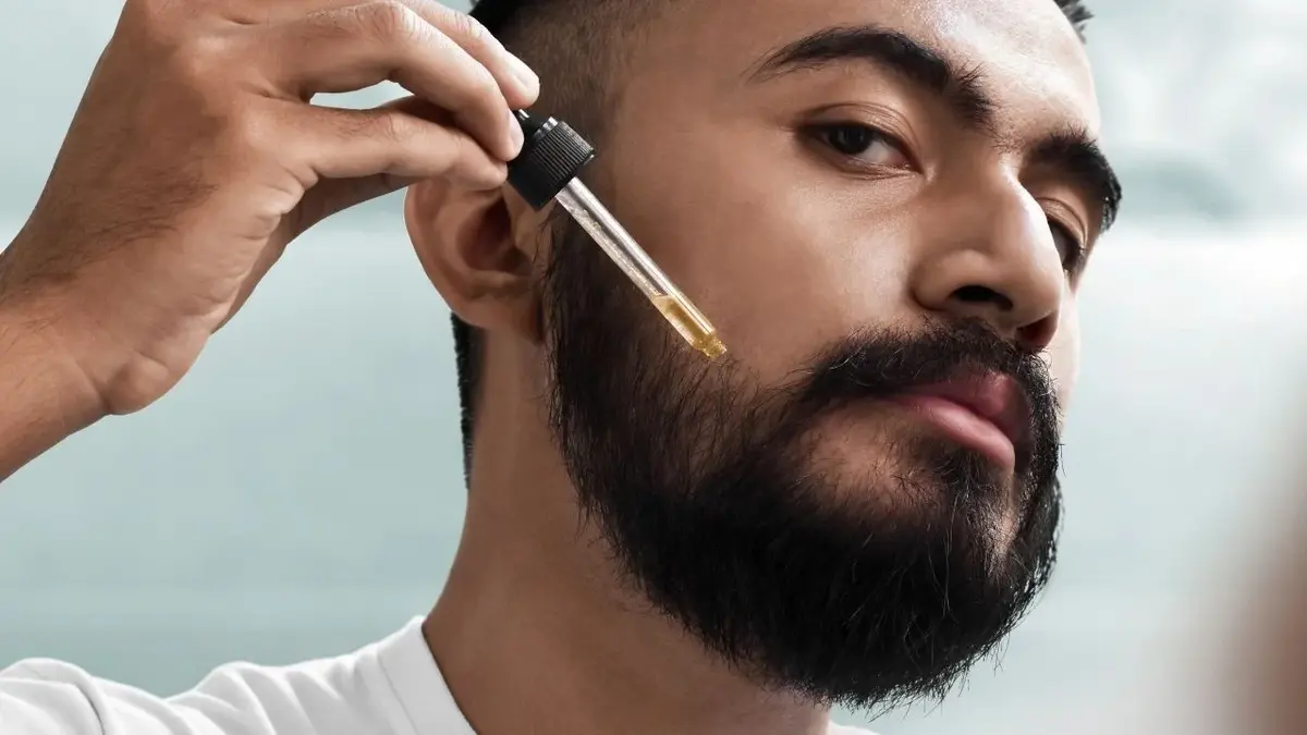 mężczyzna nakłada olejek do brody