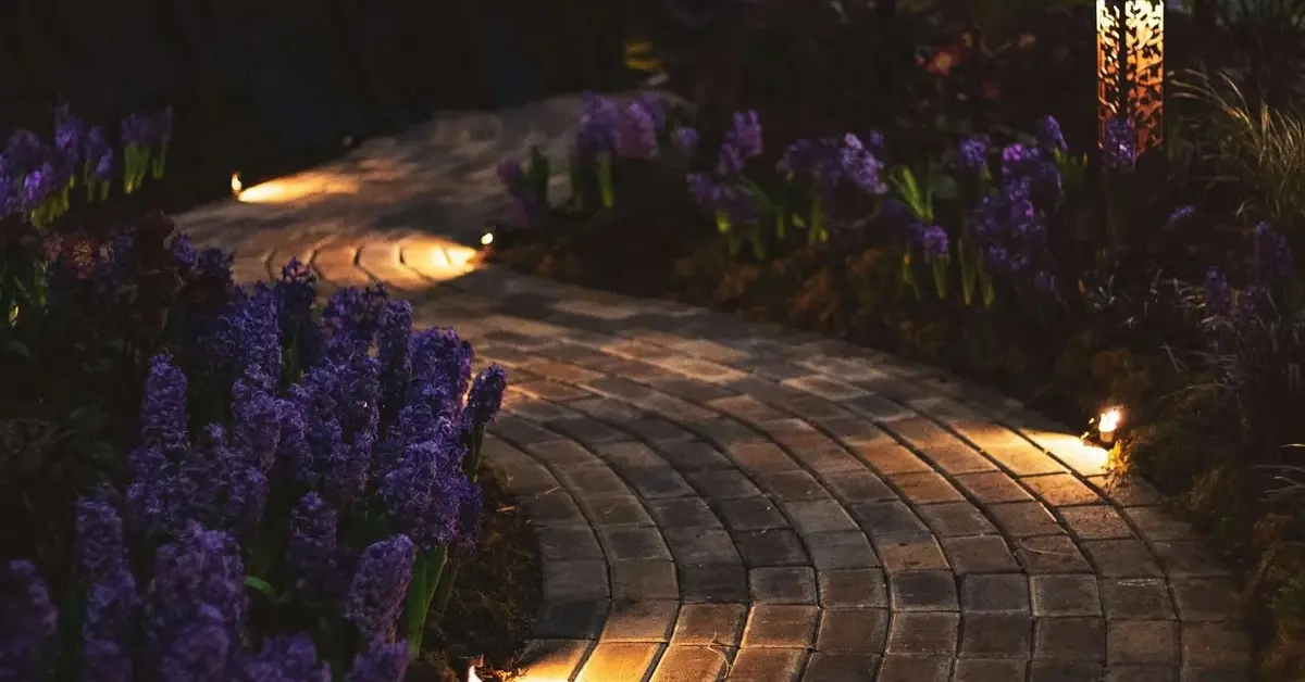 Klimatyczna alejka w ogrodzie domowym oświetlona kinkietami zewnętrznymi
