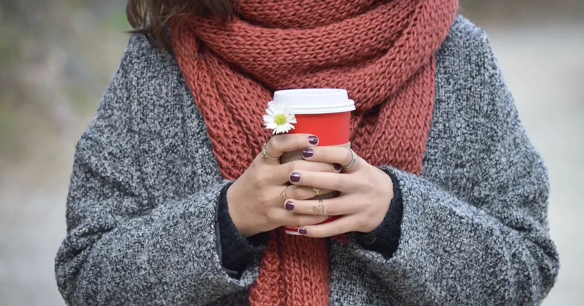 Kobieta z kubkiem w ręku i szalikiem