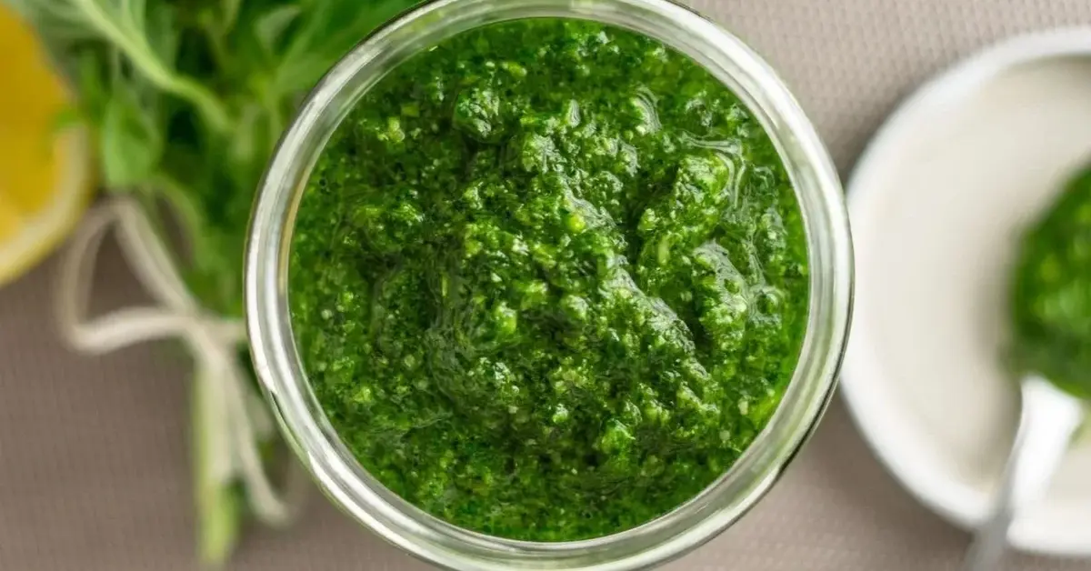 zielone pesto z orzechami brazylijskimi w szklanym słoiku