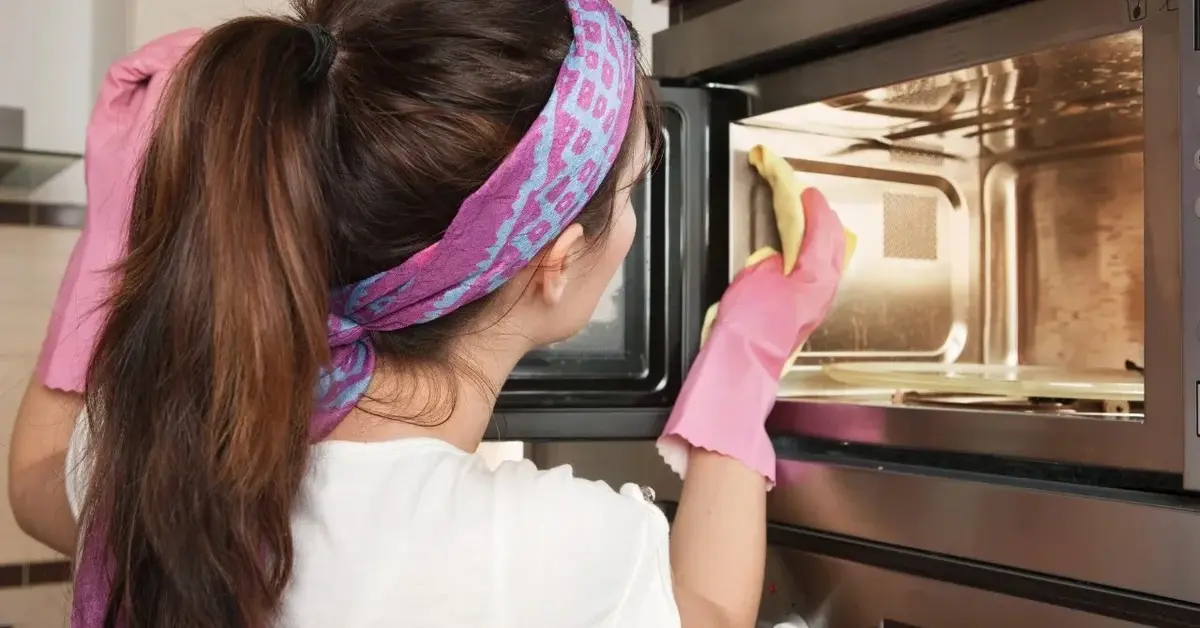 czyszczenie piekarnika kobieta czyści gąbką w rękawiczkach i oopasce