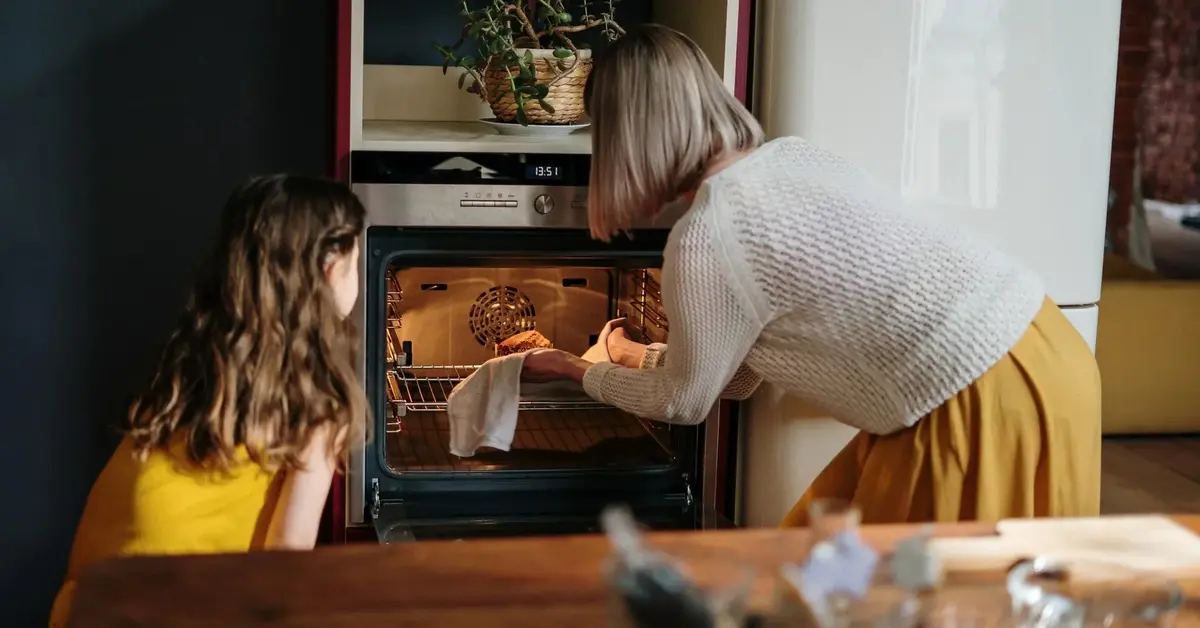 Babcia i wnuczka wyjmują ciasto z piekarnika