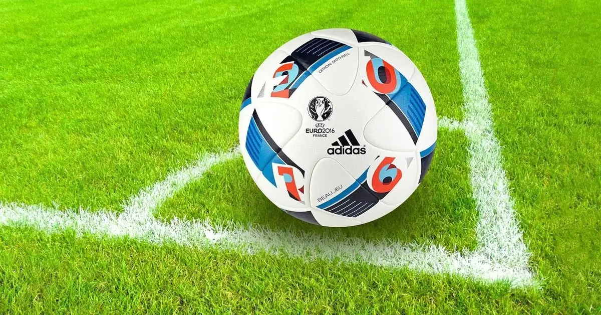 Róg zielonego boiska sportowego z umiejscowioną białą piłką do piłki nożnej