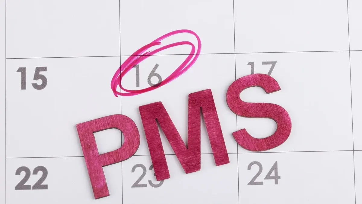 Różowy napis PMS wpisany w kalendarz.