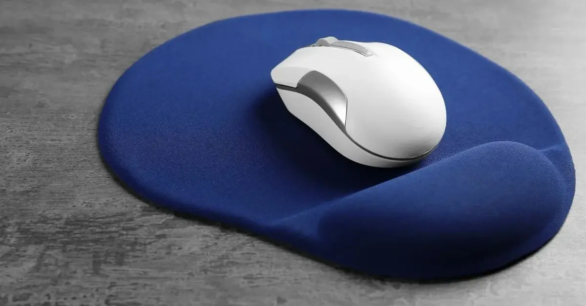 Biała myszka bezprzewodowa na niebieskiej podkładce pokrytej tkaniną