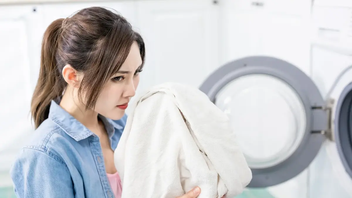 kobieta wącha ubranie wyciągając z pralki