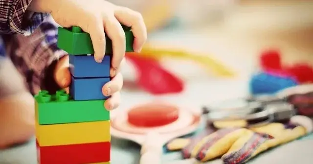 Dziecięce rączki bawiące się kolorowymi klockami jako doskonałym prezentem na roczek