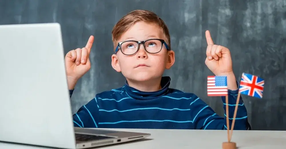 Chłopiec w okularach przed komputerem w trakcie korzystania z programu do nauki języka angielskiego 