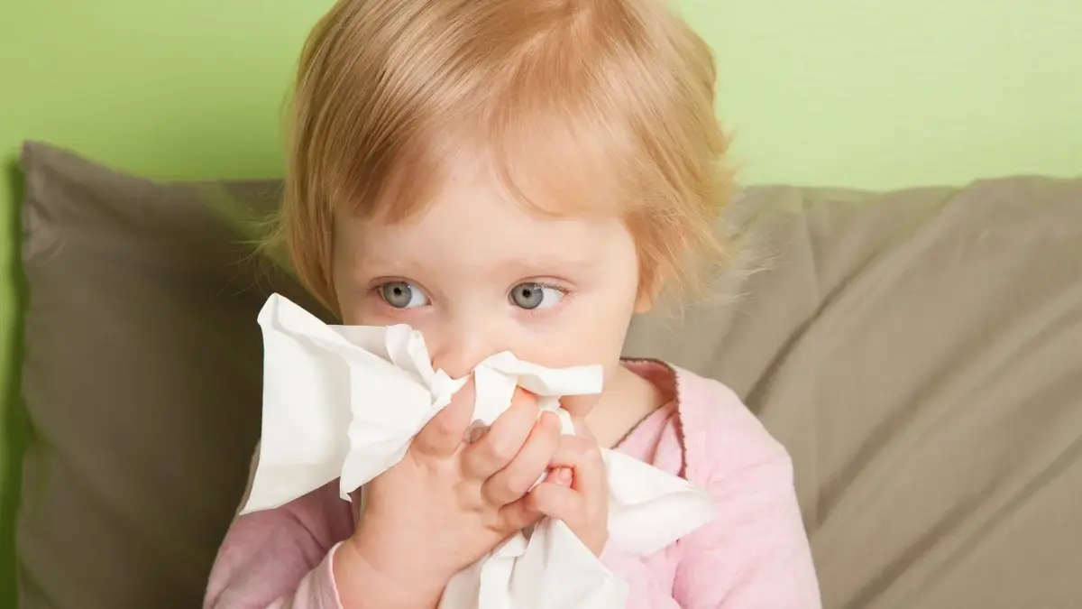 Przeziębione dziecko jest smutne i wyciera nos.