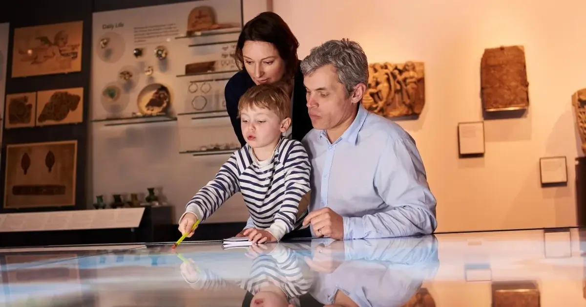 Rodzice i dziecko oglądają wystawę w muzeum podczas ferii zimowych.