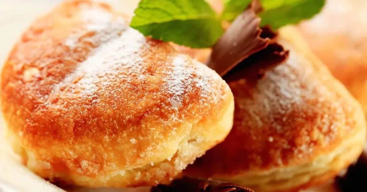 Puszyste sakiewki z ciasta serowego z nadzieniem z powideł posypane cukrem pudrem