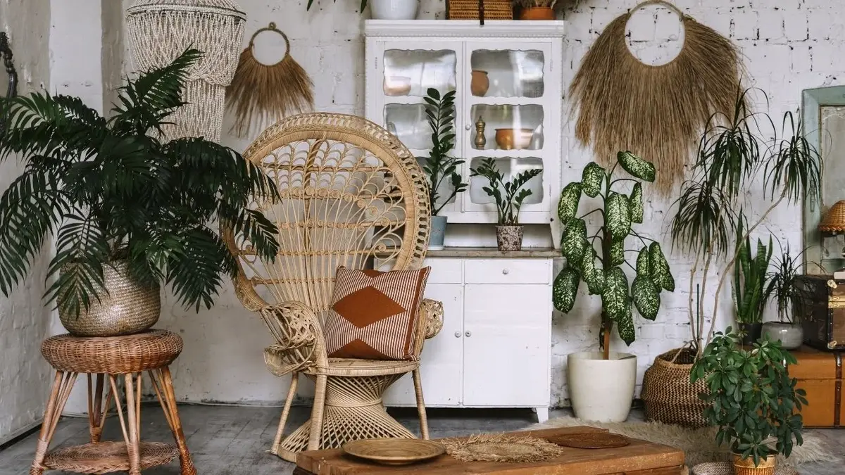 Salon boho z plecionym fotelem, białą szafką, rattanowym stolikiem i roślinami