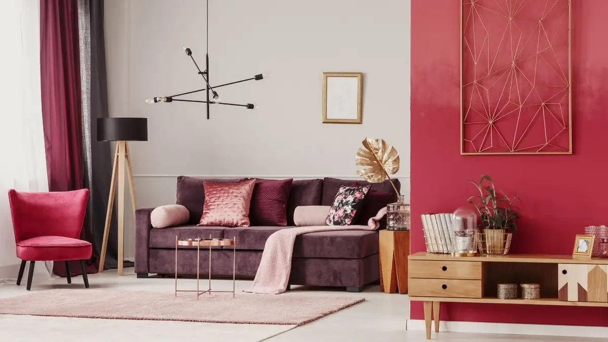 Salon z czerwoną ścianą, fioletową kanapą z poduszkami i czerwonym fotelem