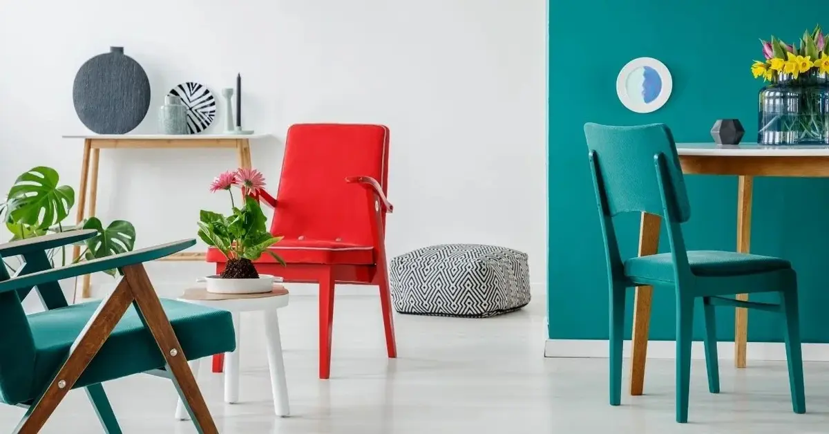 Salon z szaro-zieloną ścianą, zielony krzesłem, jednym fotelem czerwonym, a drugim zielonym