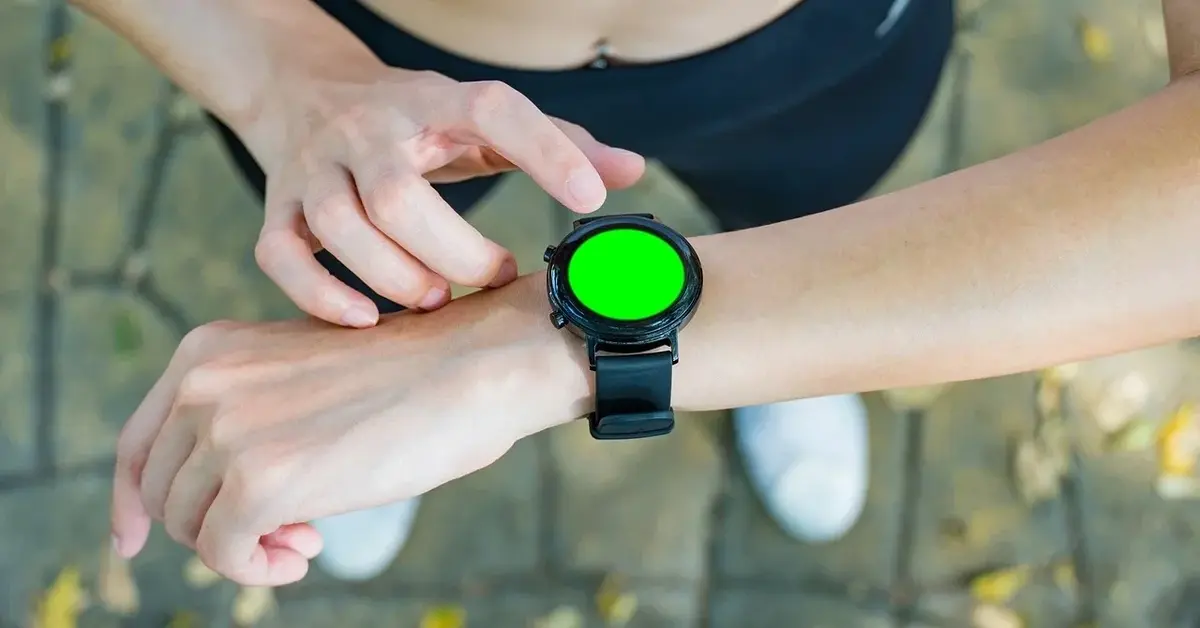 Kobiece dłonie w czasie joggingu sprawdzające dane na smartwatchu