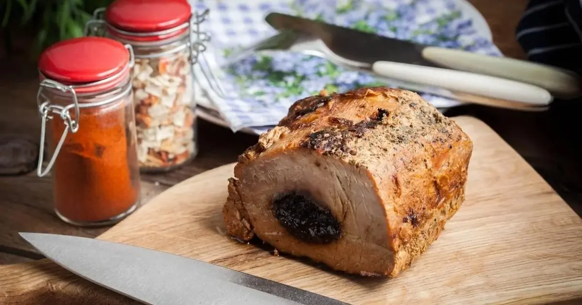 Schab ze śliwką na drewnianej desce.