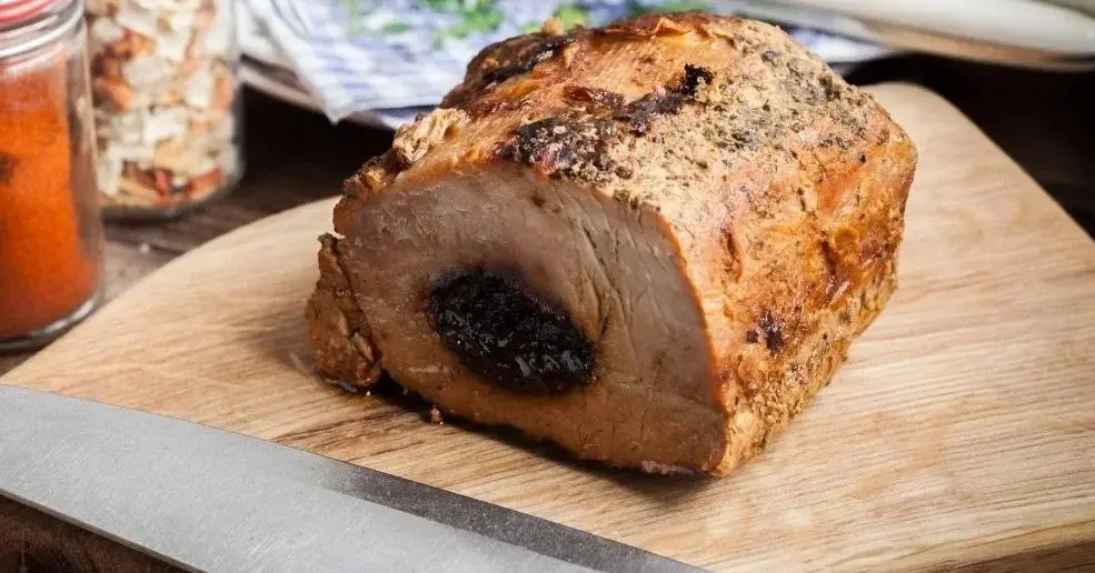 Schab ze śliwką na drewnianej desce.