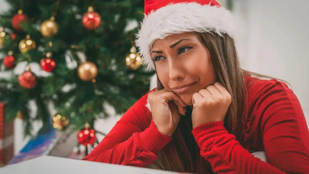 Kobieta w czapce mikołaja samotnie spędza Święta.