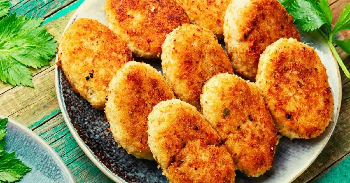 Talerz na stole pełen soczystych kotletó mielonych z niespodzianką z ogórkiem i serem