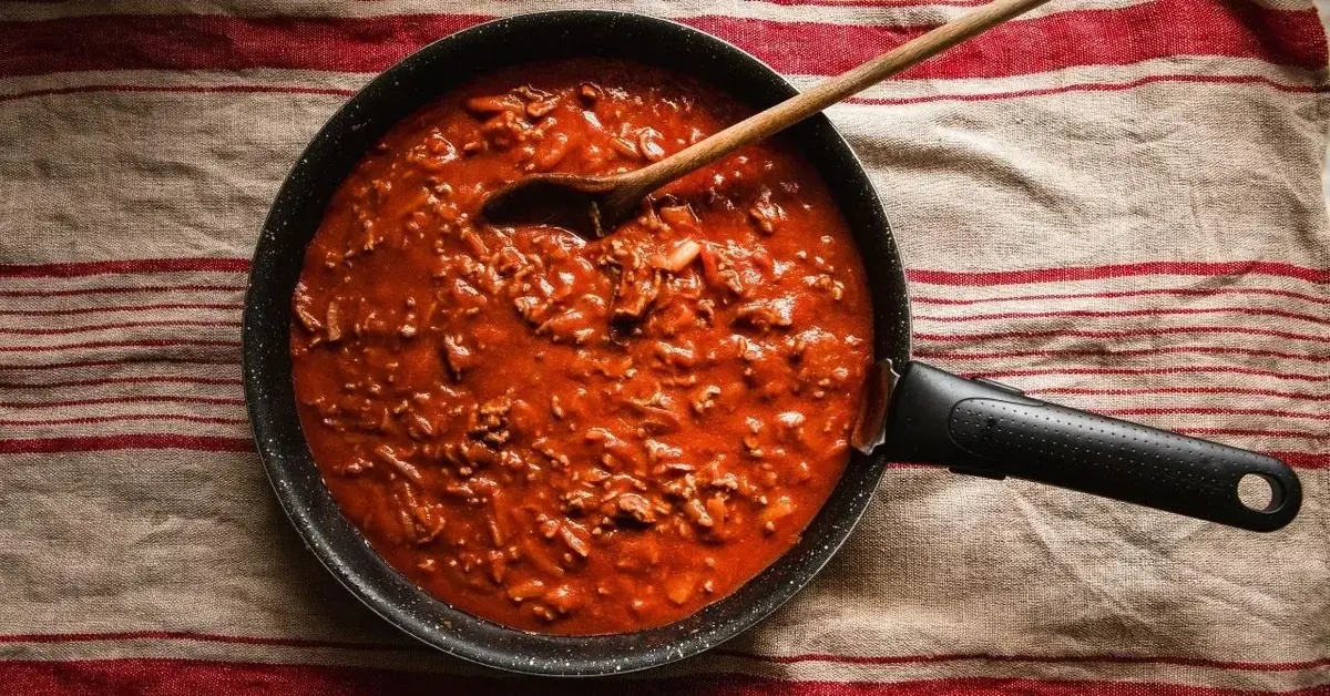 Sos boloński na patelni stojącej na ściereczce.