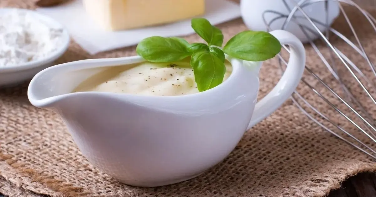 Sos chrzanowy z jabłkiem podany w białej sosjerce, udekorowany świeżą bazylią