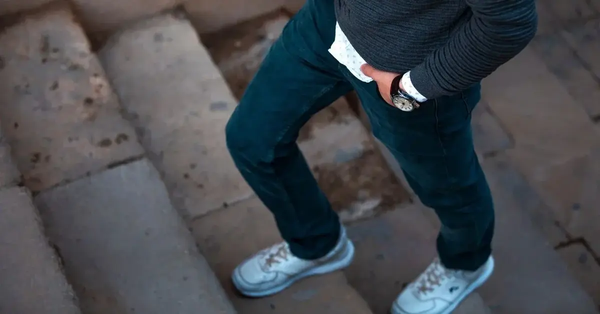 Mężczyzna wchodzący po schodach w spodniach męskich niebieskich