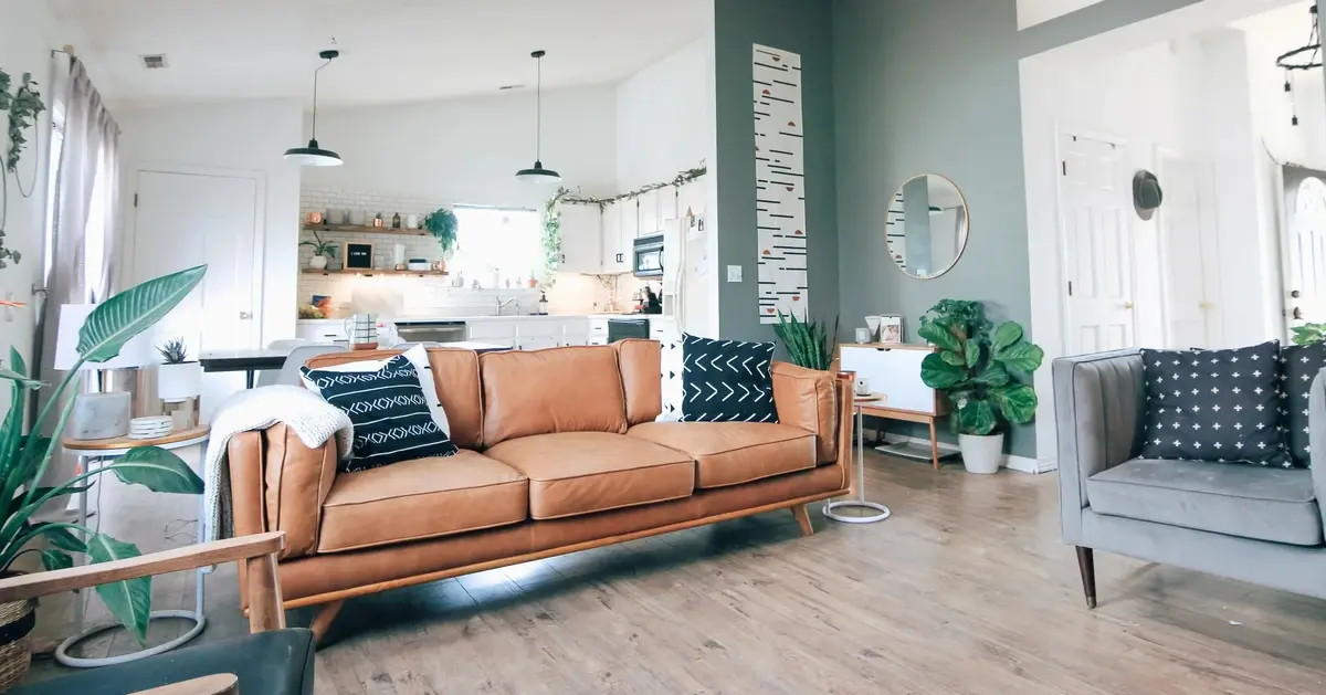 Mieszkanie w stylu skandynawskim w jasnych kolorach z jasnobrązową kanapą na środku