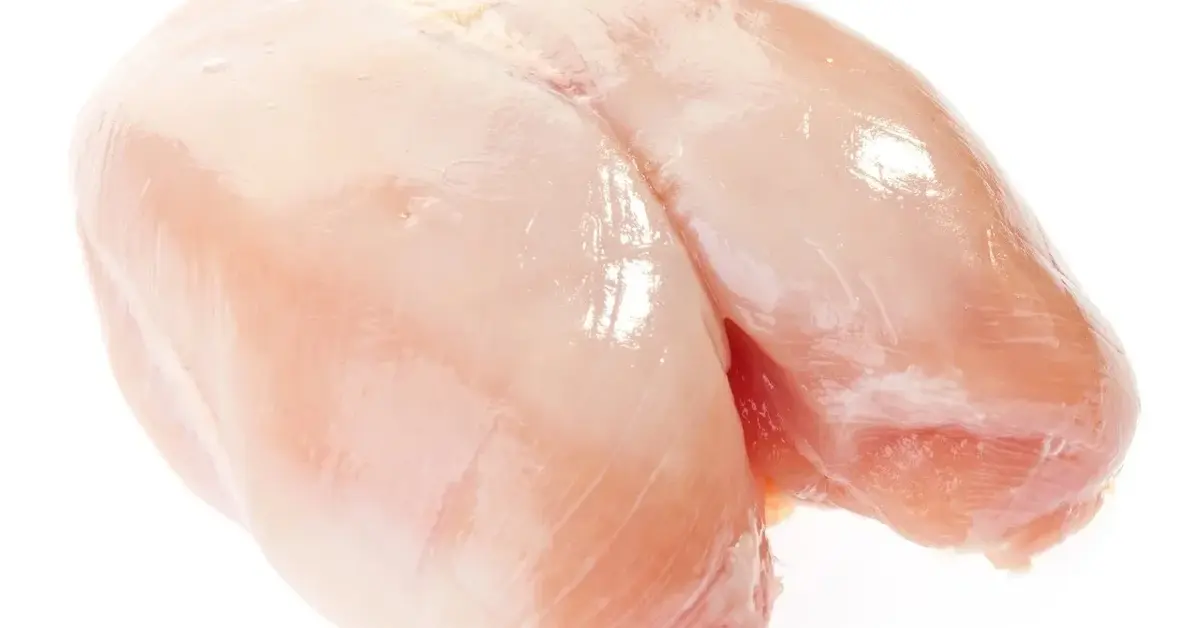 Surowa podwójna pierś z kurczaka na białym tle.