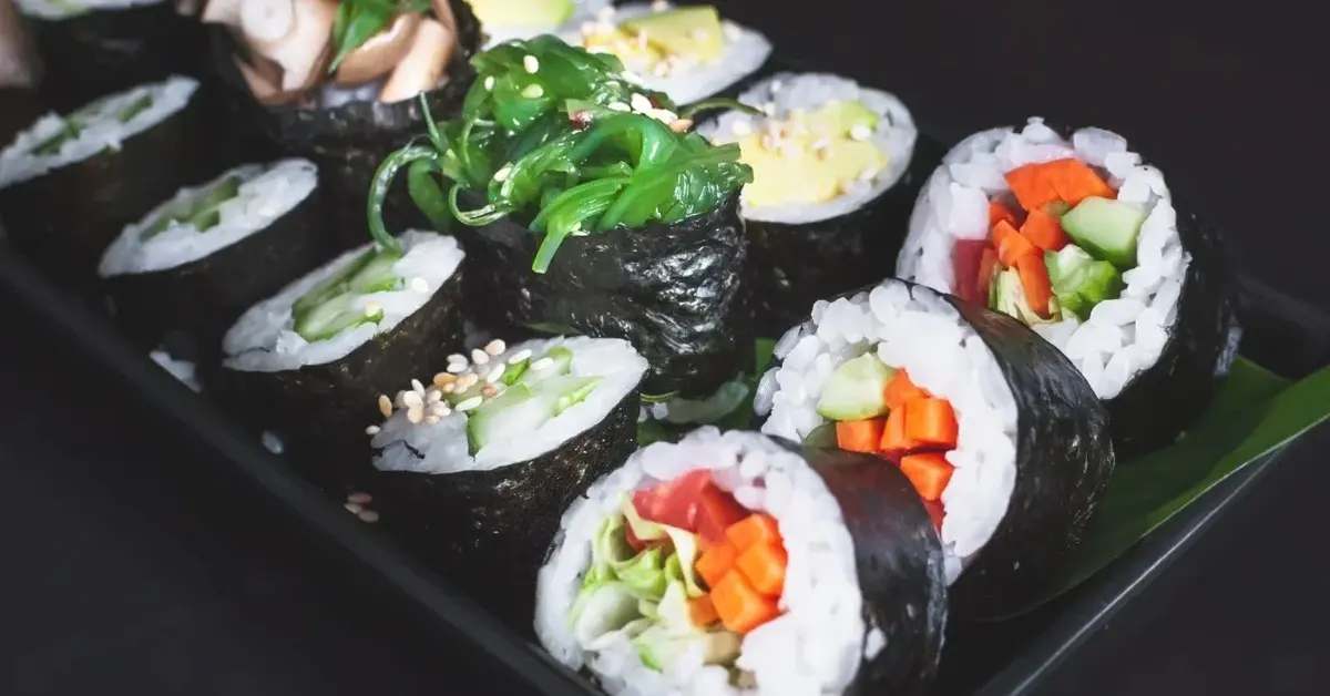 sushi rolki w trzech rzędach na czarnym talerzu
