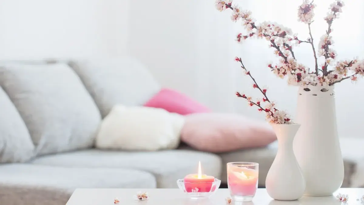 świeczki różowe i kwiaty z tyłu kanapa i poduszki różowe