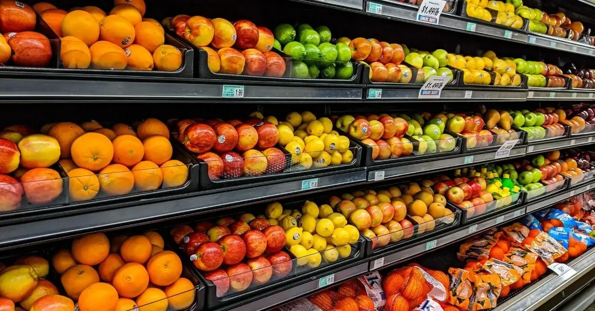 Widok na wypełnioną świeżymi kolorowymi pięknymi owocami idealną szafę chłodniczą w alejce sklepowej