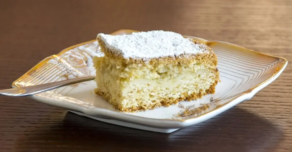 Anielska szarlotka siostry Anieli, posypana cukrem pudrem, podana na porcelanowym talerzyku